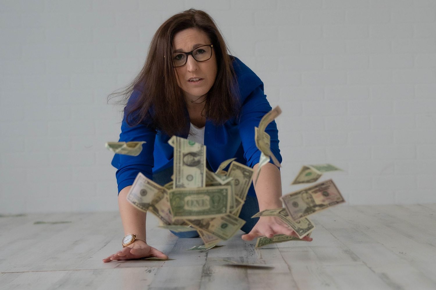 Person in blue shirt counting money on a white surface.