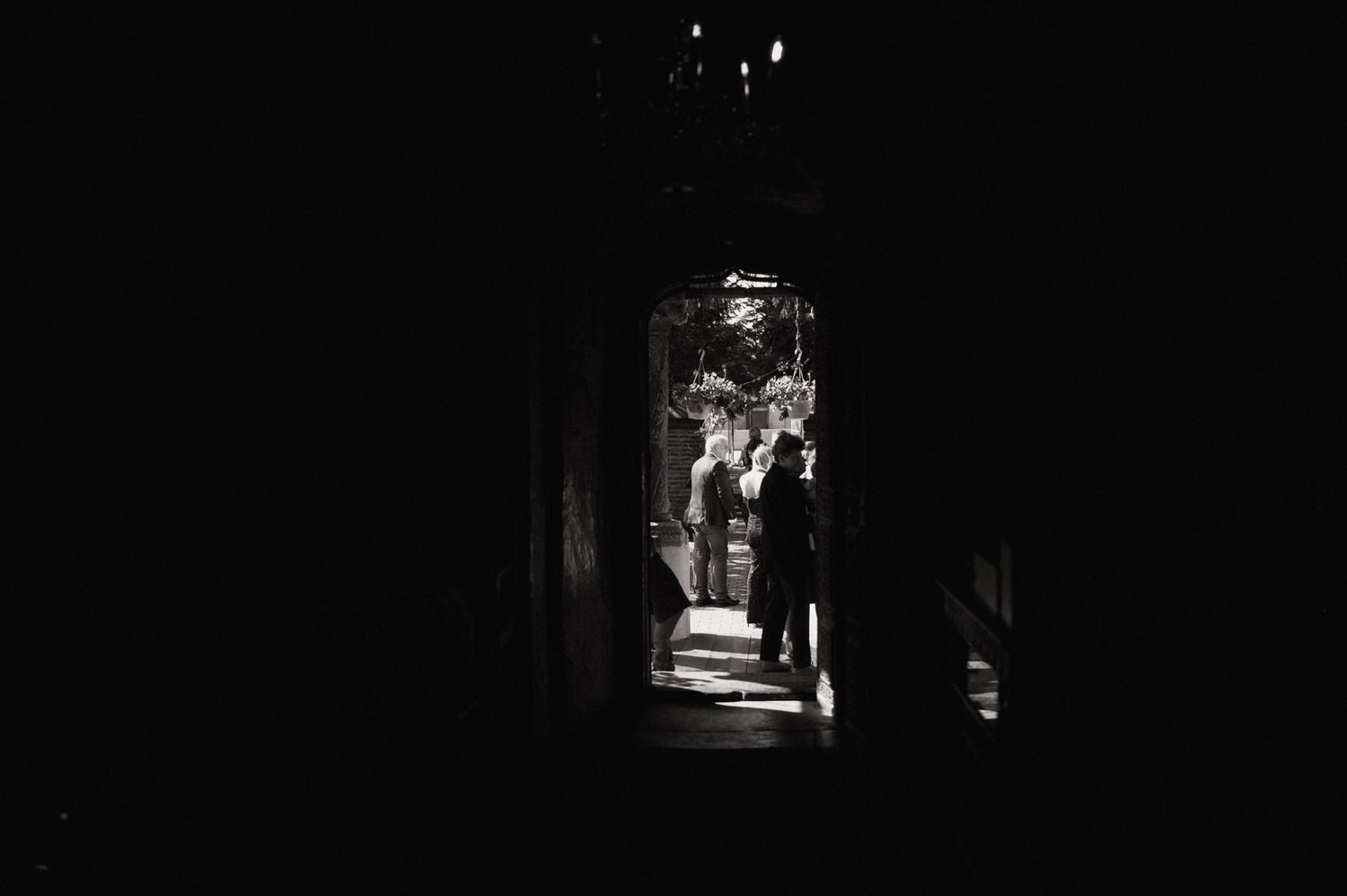 A series of black and white photographs showing dark silhouettes walking through shadowy doorways and corridors.