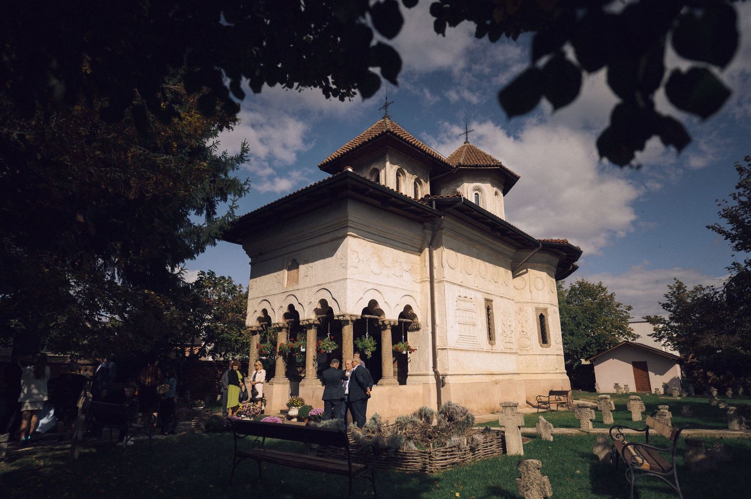 A series of six connected photos showing a traditional Romanian Orthodox church with white walls and dark roof in daylight.