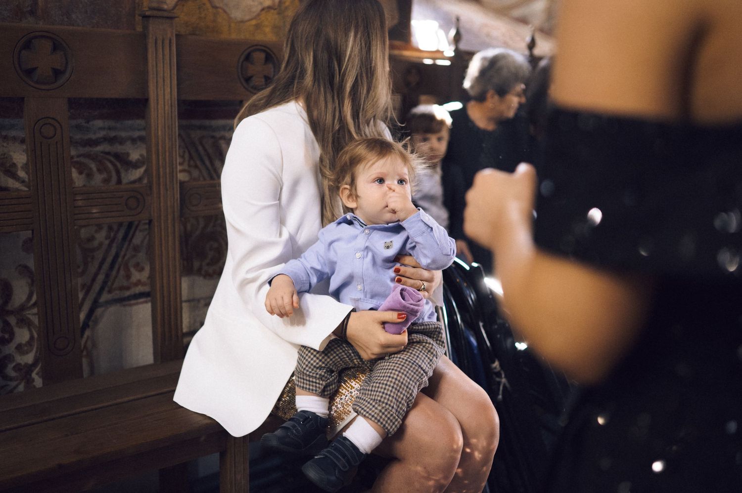 A child sits on someone's lap while wearing a light blue outfit in an ornate indoor setting.