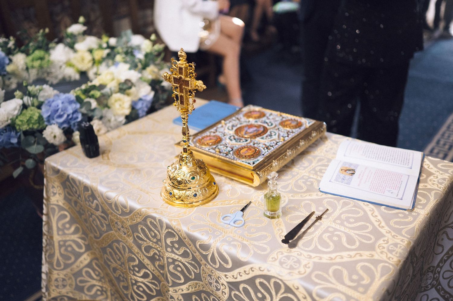 Gold and white patterned tablecloths with elegant place settings at a formal dining event.