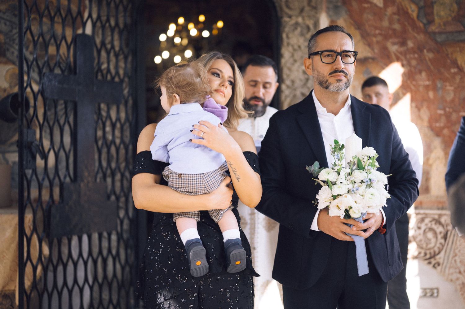 Wedding party members share joyful embraces and moments together in a rustic venue with warm lighting.