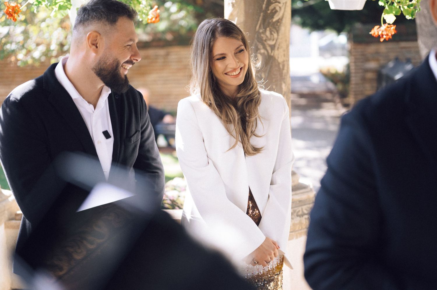 A couple shares a joyful moment together outdoors while dressed in elegant black and white attire.