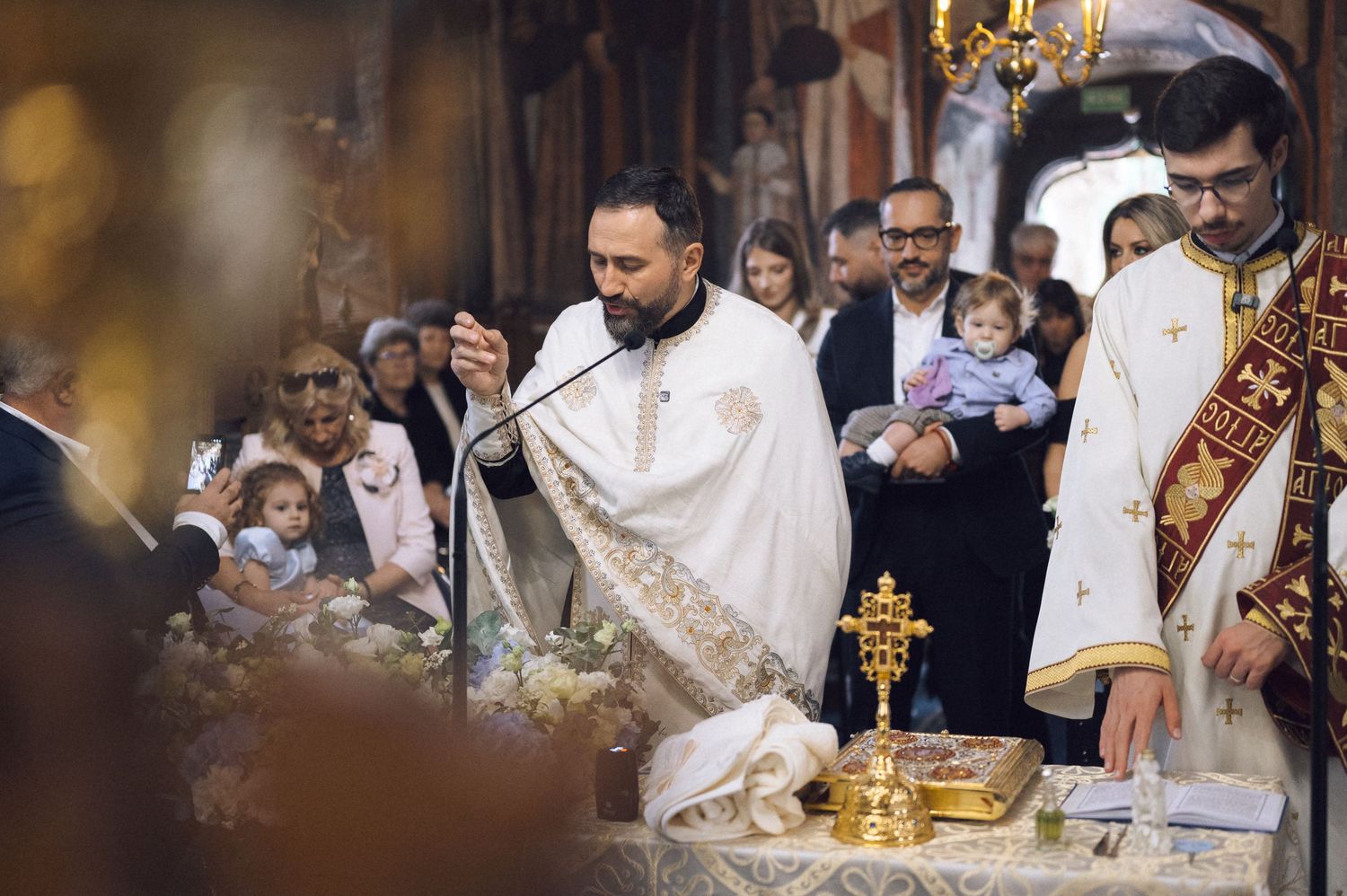 Orthodox Christian wedding ceremony with priest performing traditional rituals at ornate church altar.
