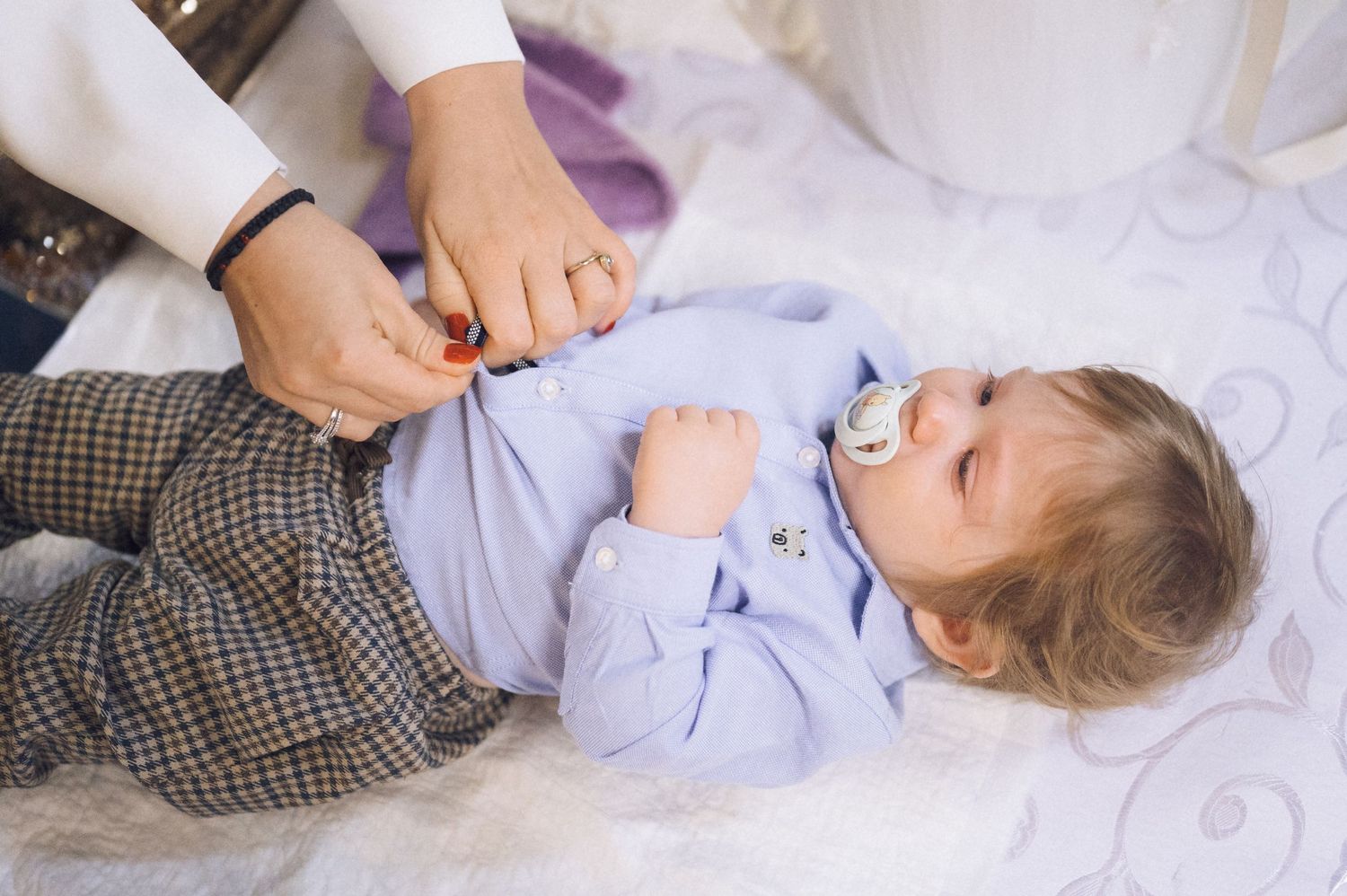 Sequence of photos showing a child lying on white bedding while playing with a toy or pacifier.