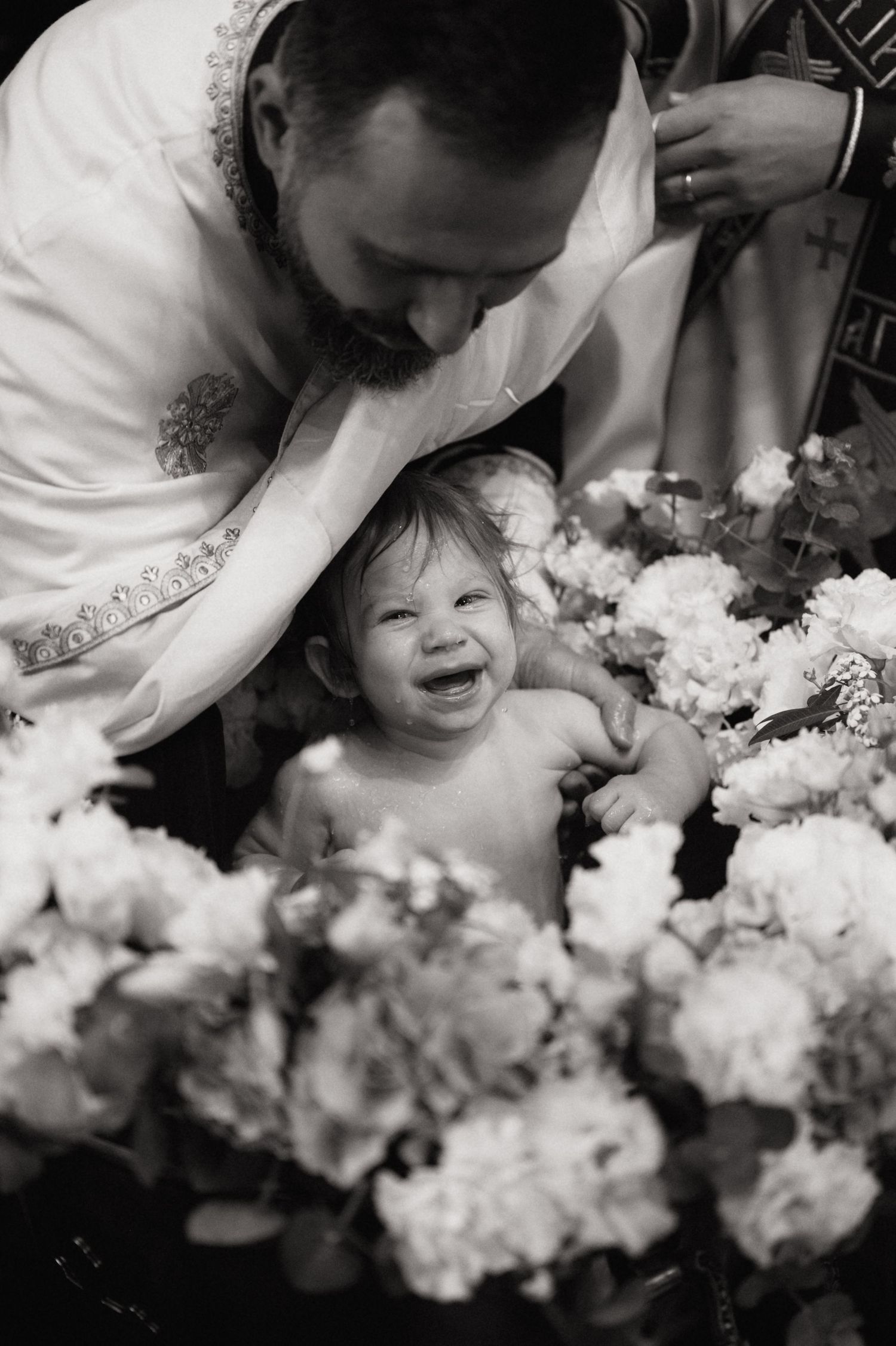 Black and white photo series showing joyful moments between parent and child surrounded by delicate white flowers.