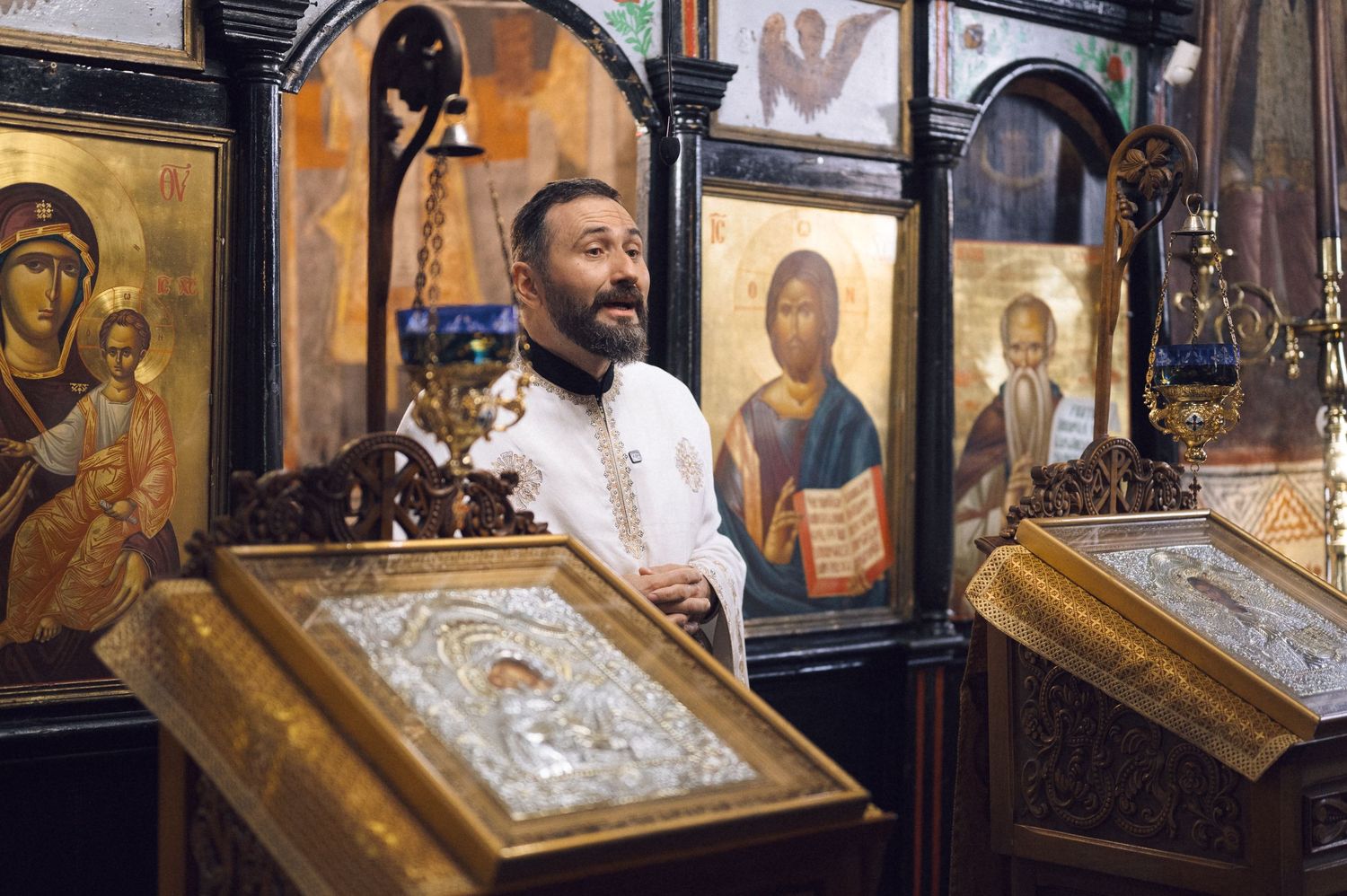 A collection of ornate religious icons and paintings displayed in gilded frames against a dark background in a gallery.