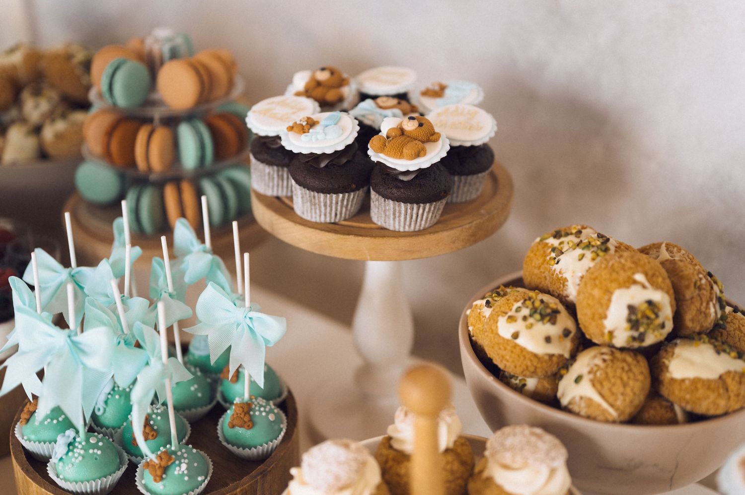 Elegant dessert table display featuring cake pops, cupcakes and pastries in soft turquoise and white colors.