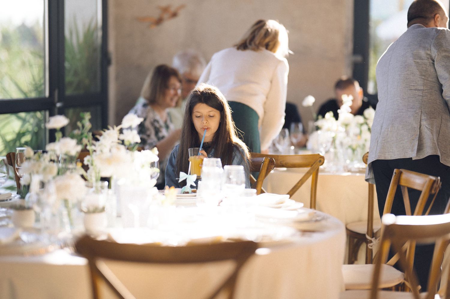 Guests seated at elegant dining tables in a bright restaurant with natural lighting and white tablecloths.