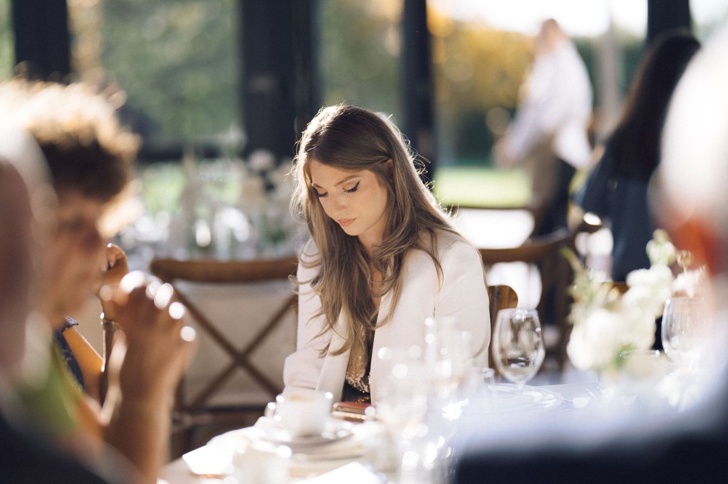 People enjoying wine and conversation at an elegant tasting event with natural lighting and glassware.