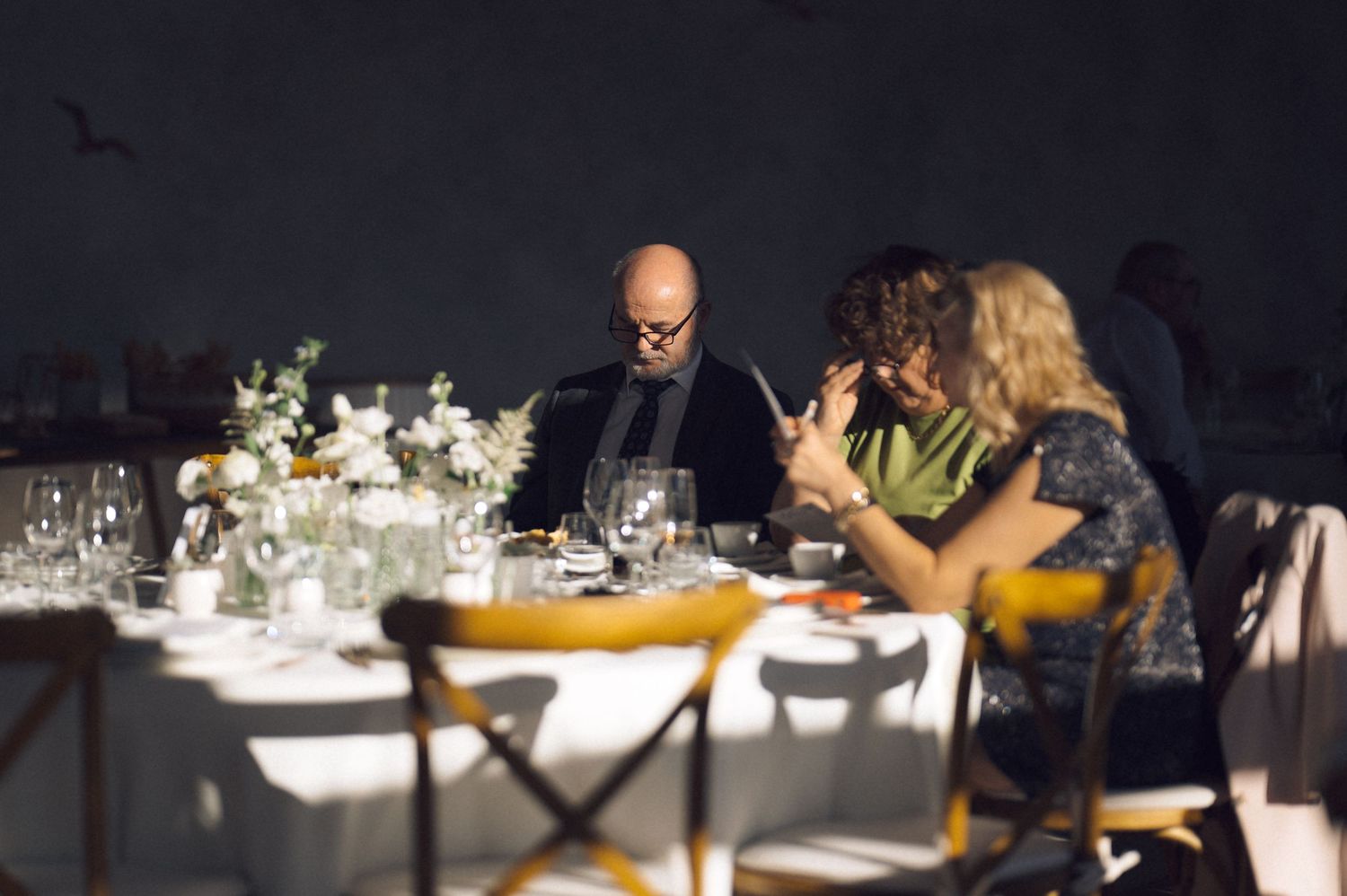 Elegant dining tables set with white linens and glassware in a dimly lit restaurant interior.