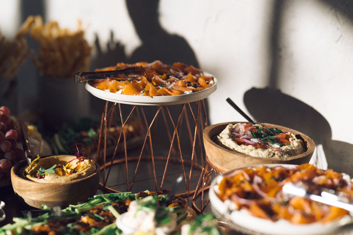 Assorted gourmet dishes and appetizers served on wooden platters with dramatic lighting and shadows.