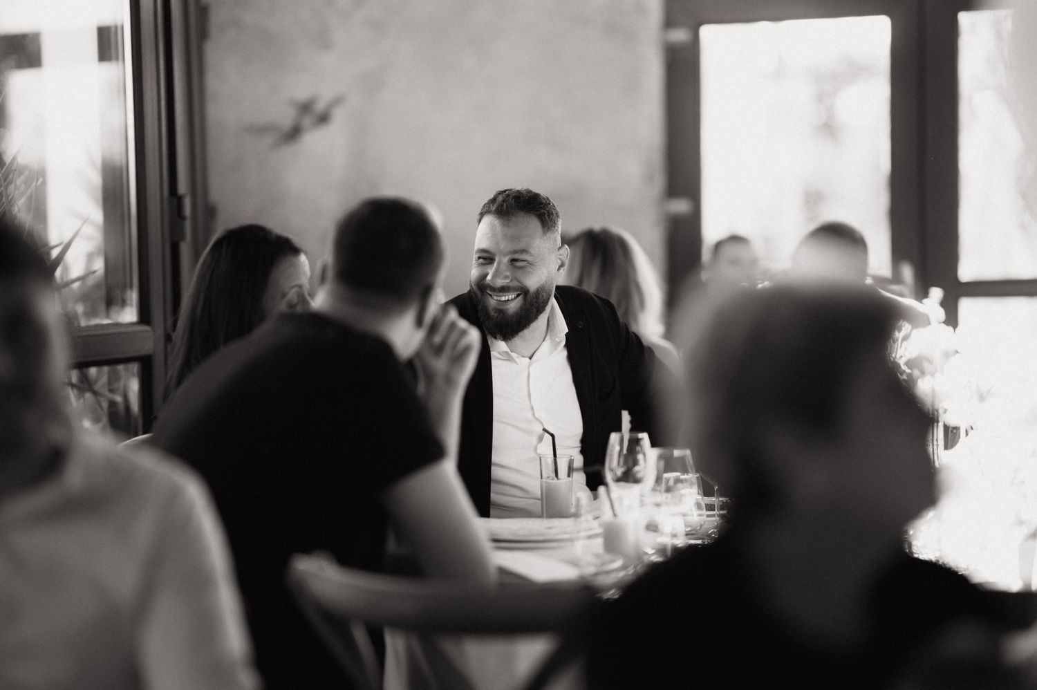 Black and white panoramic photo showing people gathered at a bar counter in a casual dining setting.