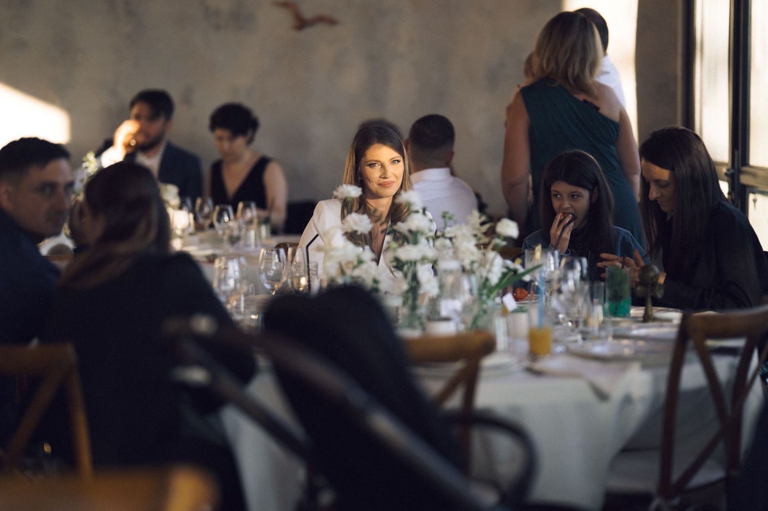 People seated at long tables during a formal dinner event in a dimly lit restaurant setting.