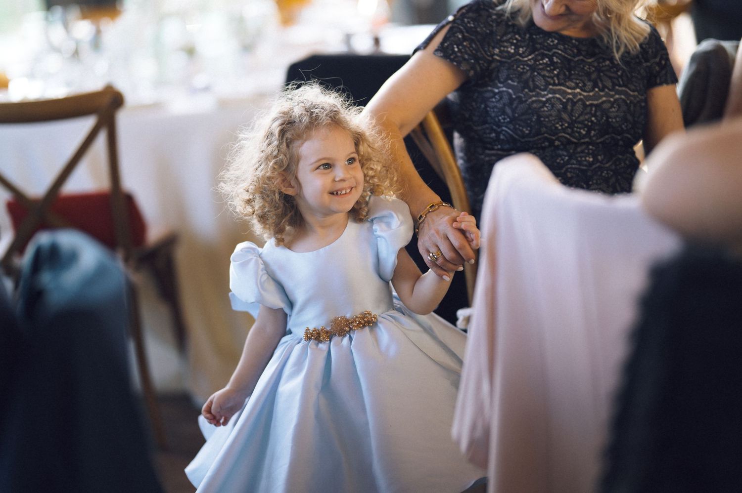 A young girl in a white dress twirls and dances at a celebration event.