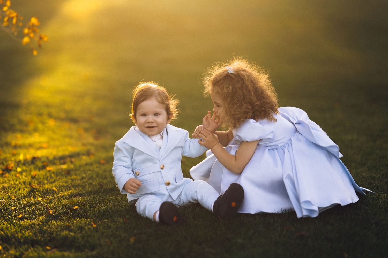 Children playing together in a sunlit meadow with golden wildflowers during sunset.