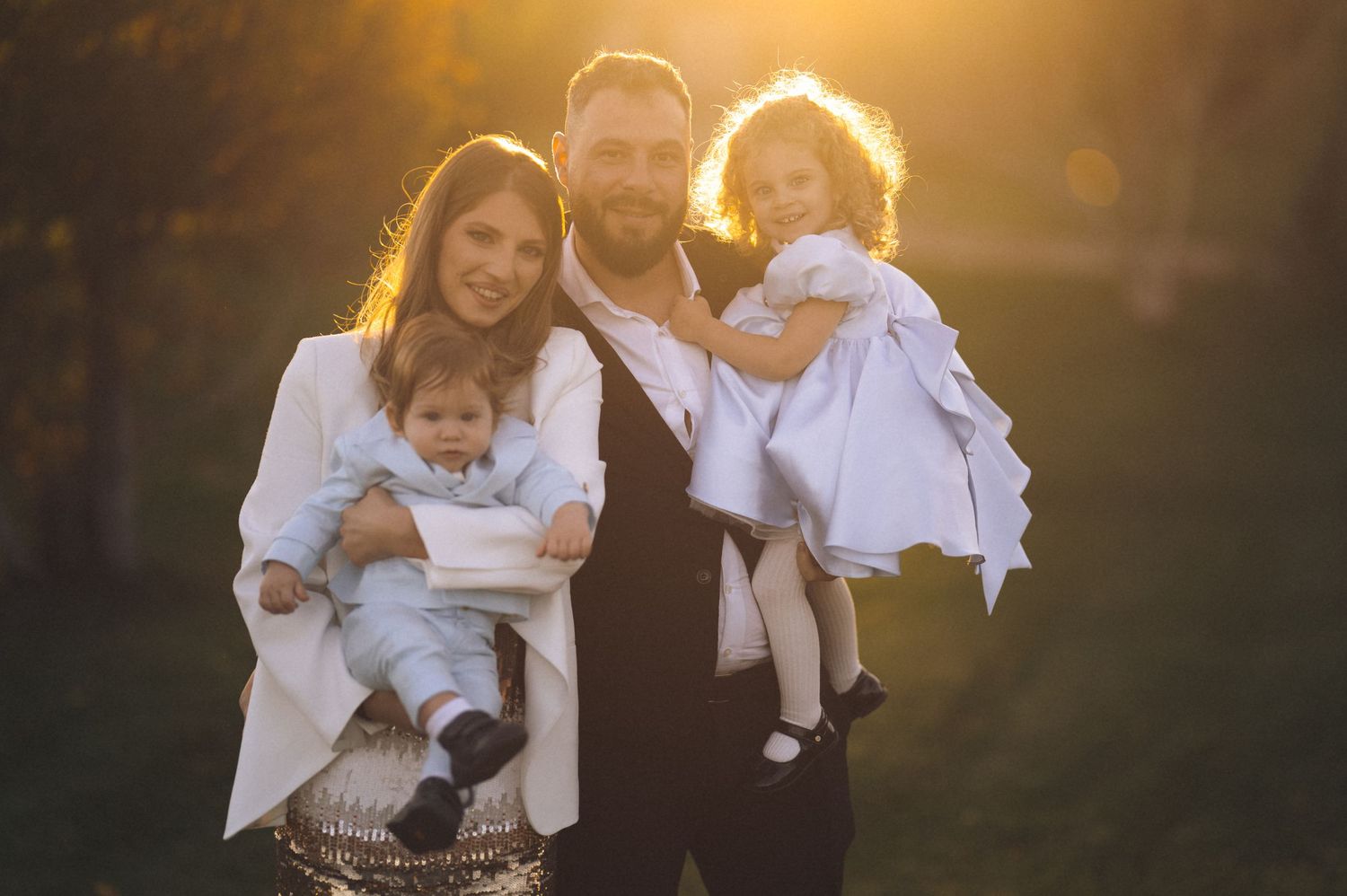 Family wearing white clothing poses together during golden hour sunset photo session outdoors.