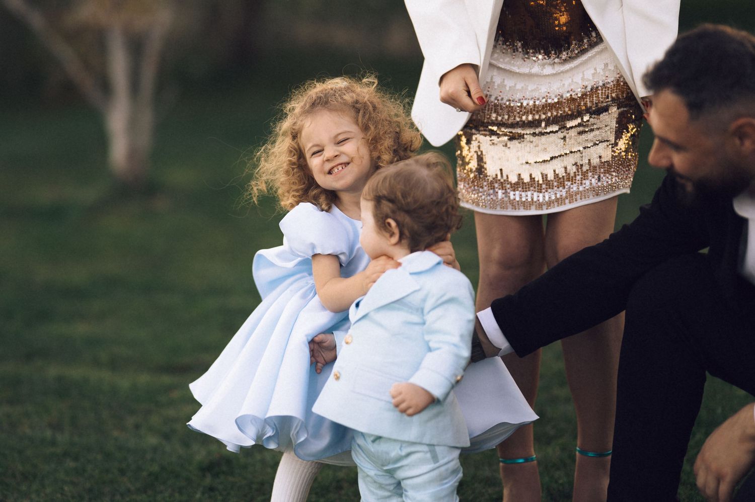 A candid outdoor family moment on a grassy lawn with people wearing casual clothing and enjoying time together.