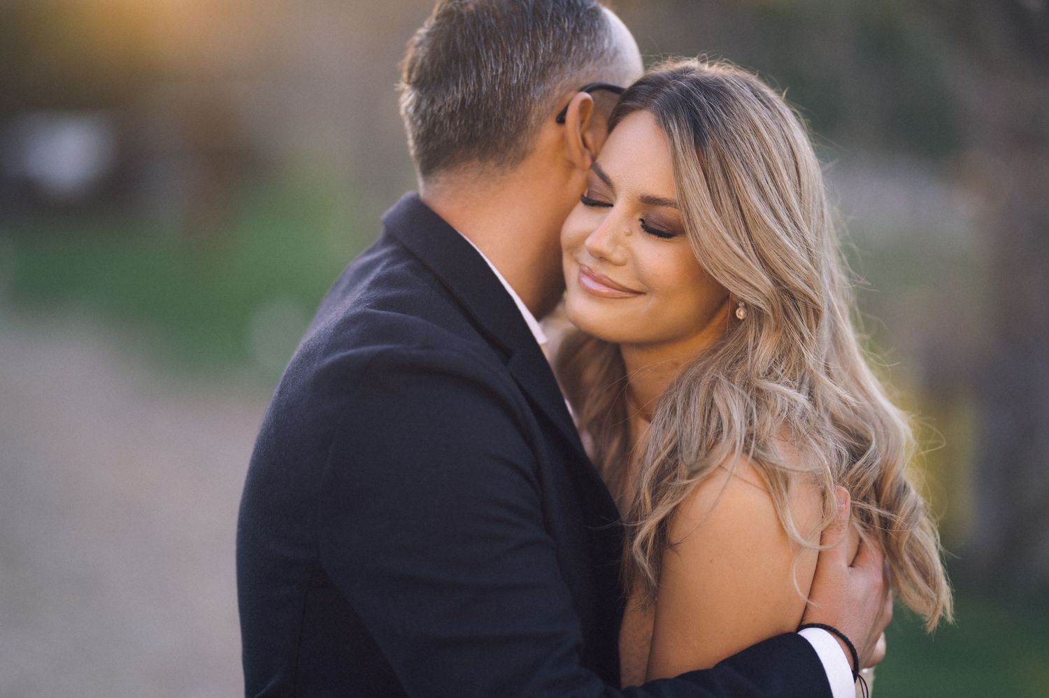 A romantic couple shares tender moments in a garden setting during their wedding photoshoot.