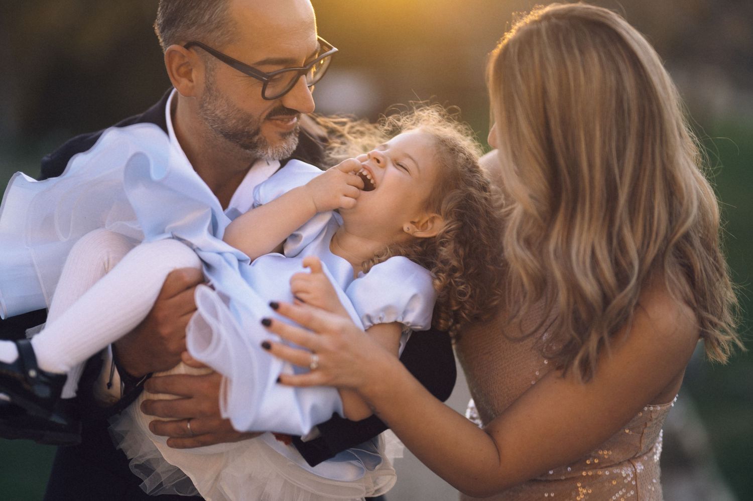 A happy family shares a joyful moment together outdoors during golden hour lighting.