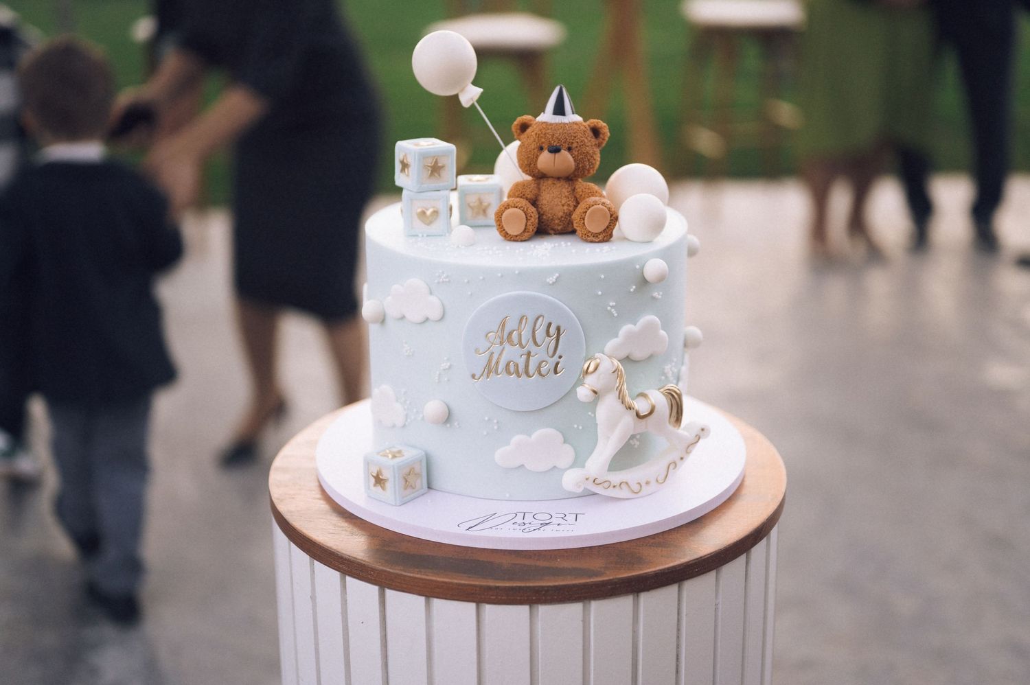 A series of white wedding cakes decorated with delicate details, flowers, and miniature bear toppers on display.