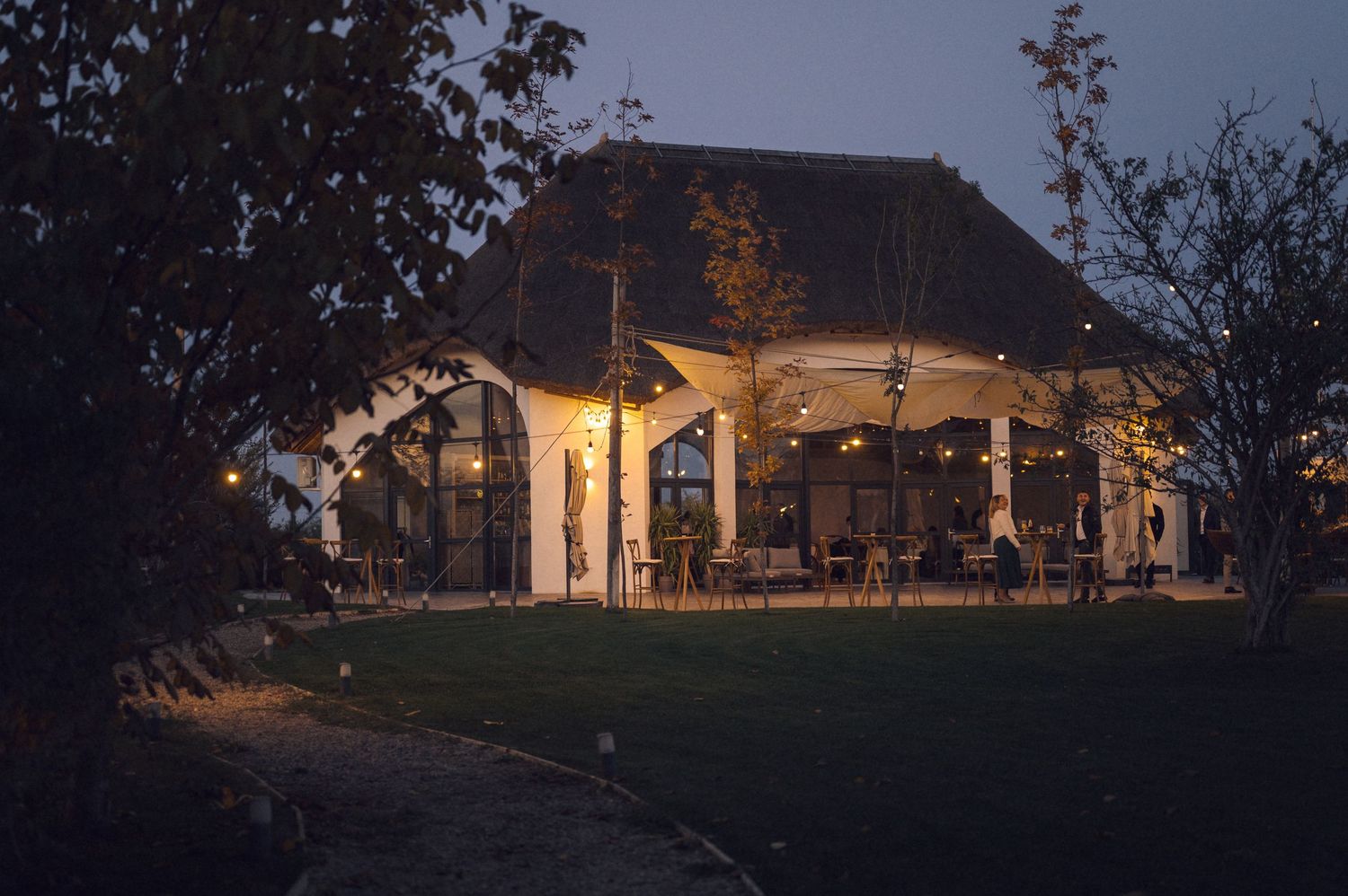 A rustic wooden lodge illuminated at dusk with warm exterior lighting and a scenic natural backdrop.