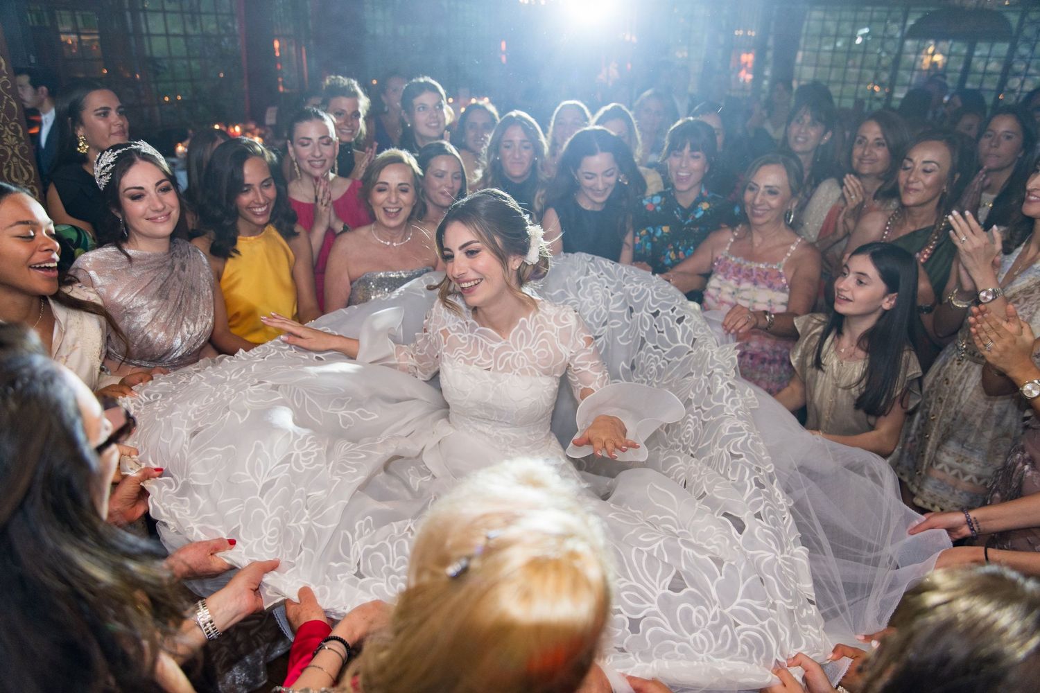 Mariée portée en cercle par les invités pendant les horots lors d’un mariage juif, ambiance festive et lumineuse.