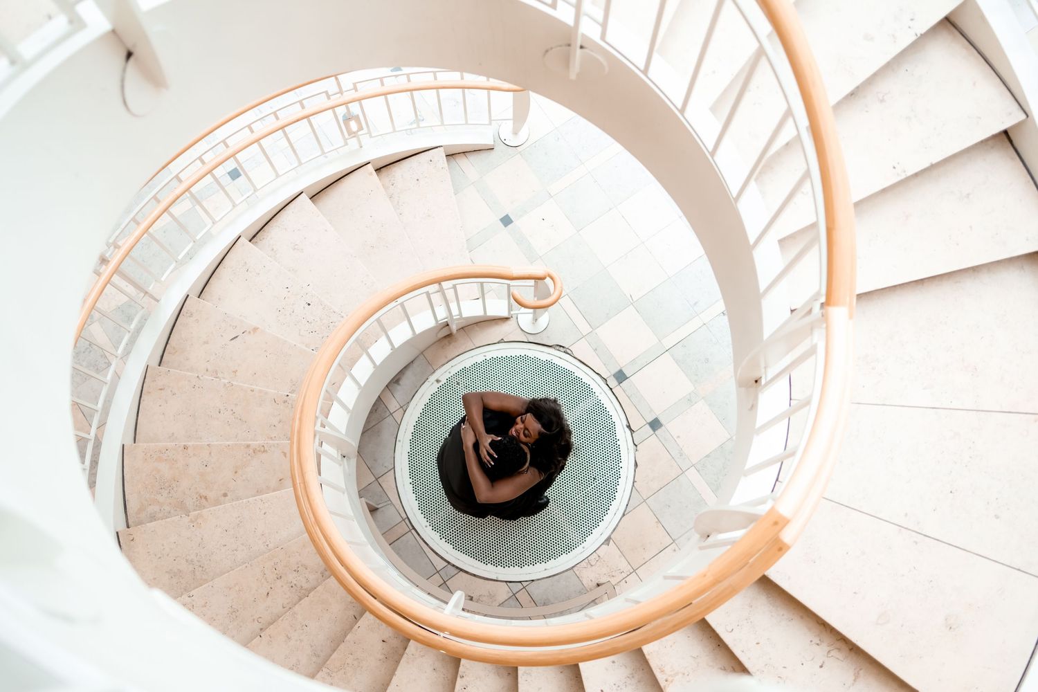 Aerial view of a modern white spiral staircase with curved wooden handrails and circular design pattern.