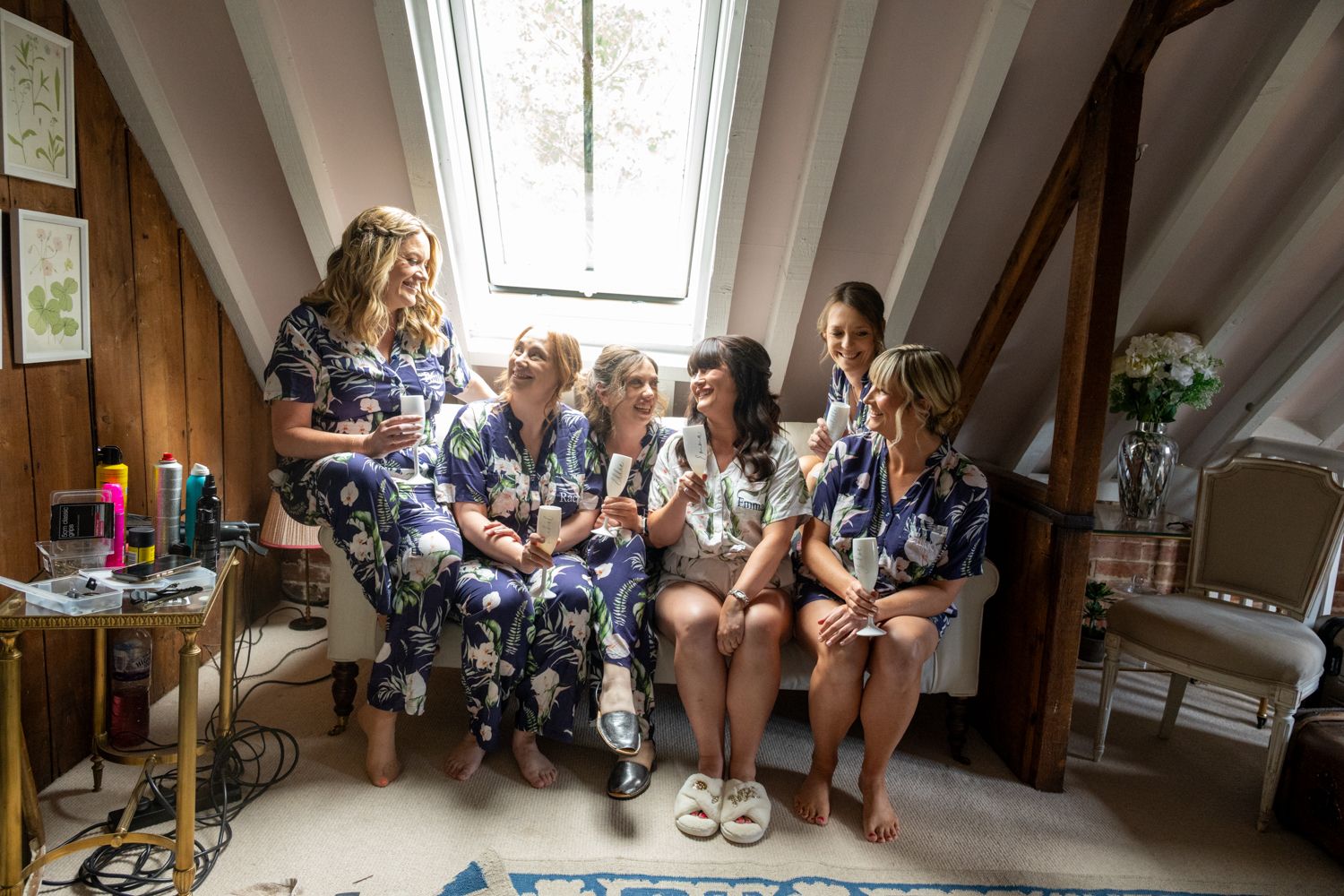 Wedding party gathered in rustic brick venue with exposed beams and natural light streaming through windows.