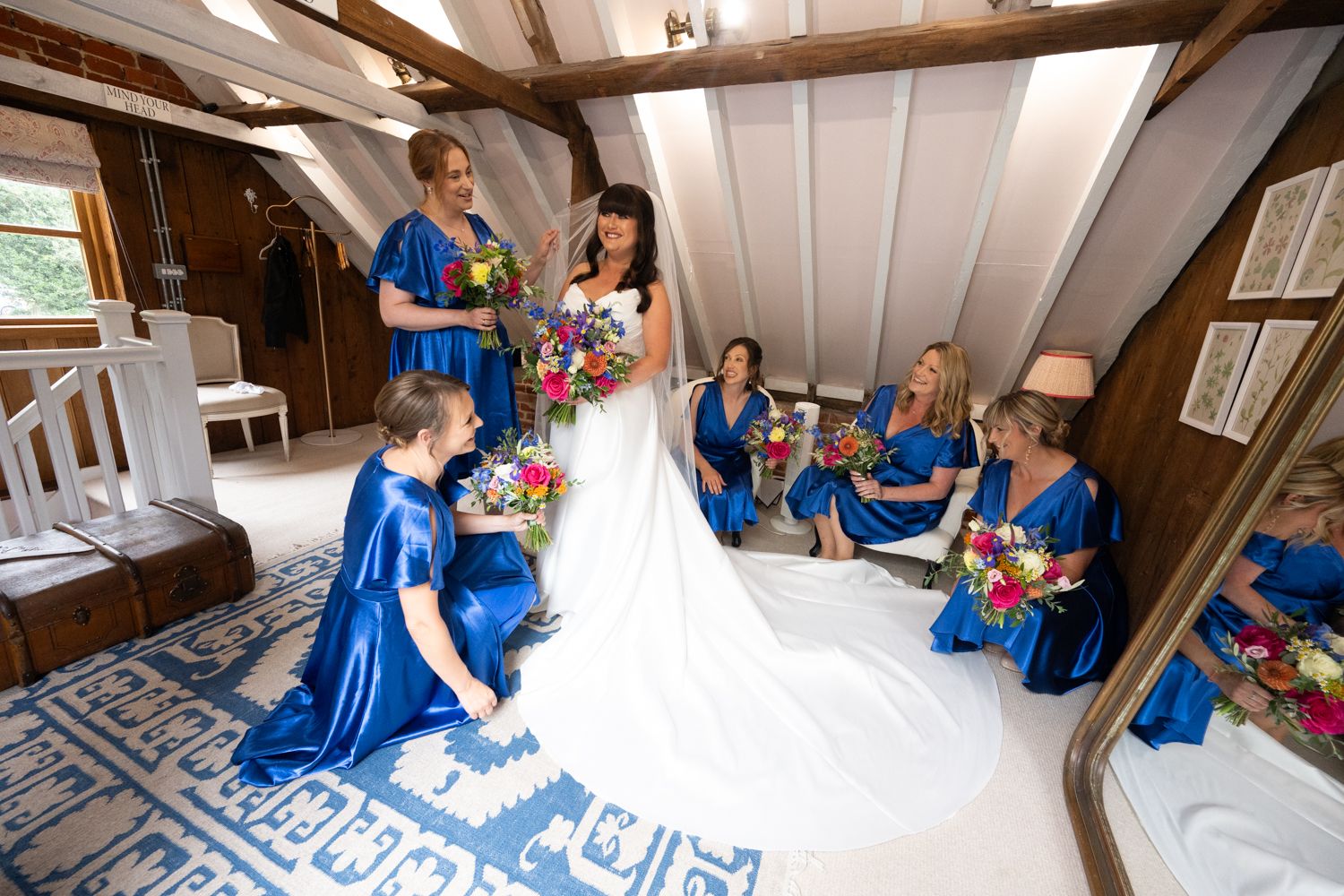 Wedding preparations taking place in a rustic white-beamed room with people in blue attire.