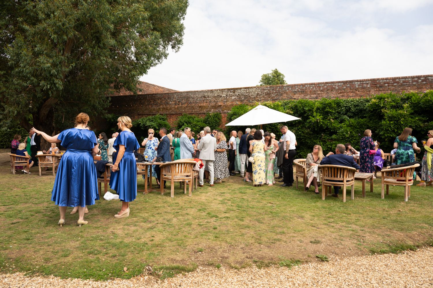 Panoramic view of people gathered at a rustic outdoor event venue with wooden structures and natural surroundings.