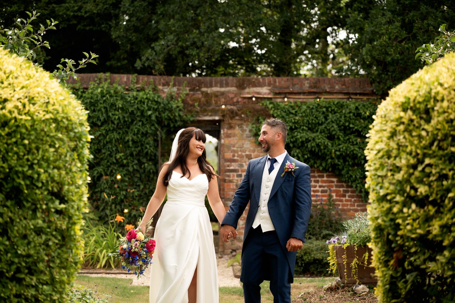 A couple shares a romantic moment in a lush garden setting during their wedding celebration.