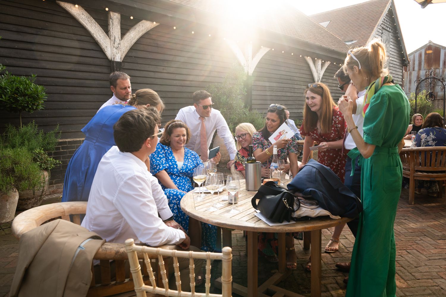 People gather at outdoor tables on a patio during a sunny afternoon social event.