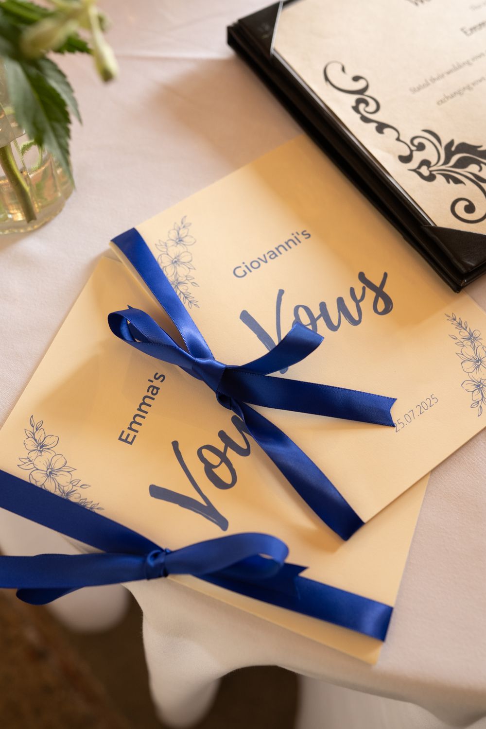 Elegant wedding invitations with royal blue ribbons arranged in a row on a white surface.