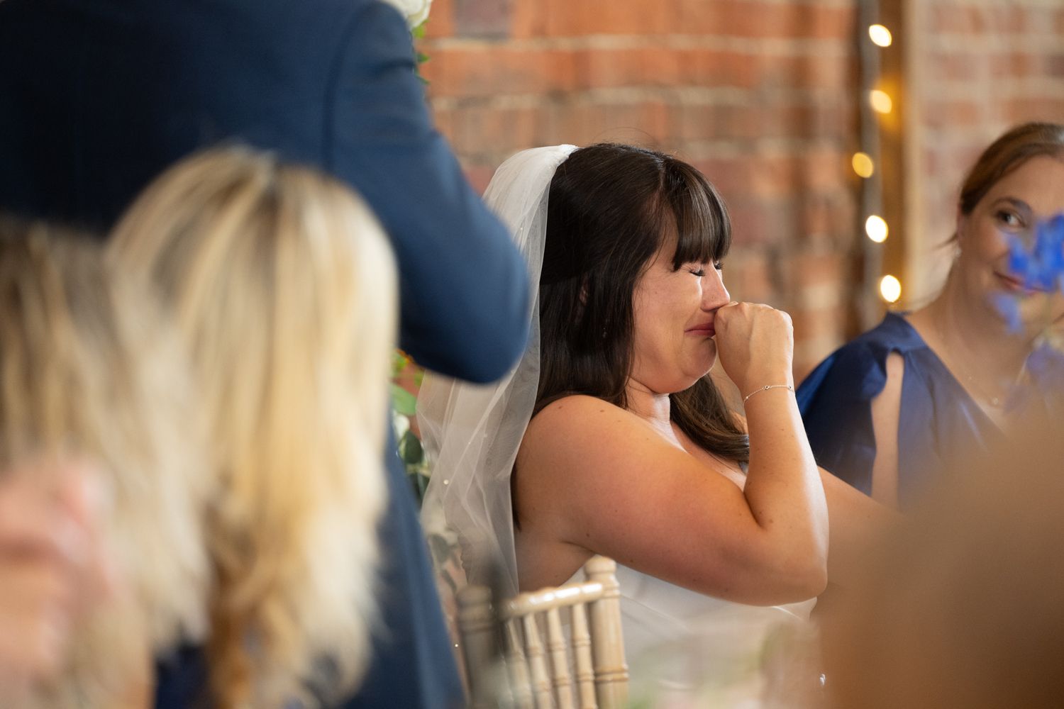 A group of people enjoying drinks and conversation at a social gathering with bokeh lights in the background.