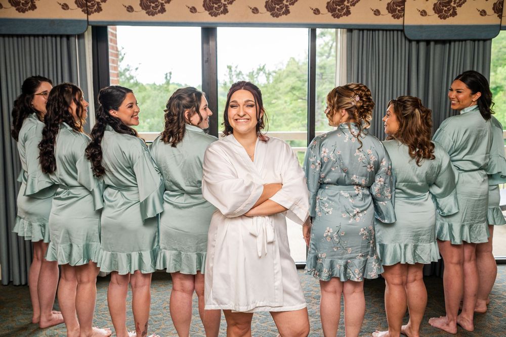 Bridesmaids in matching mint green robes getting ready together in a bridal suite.