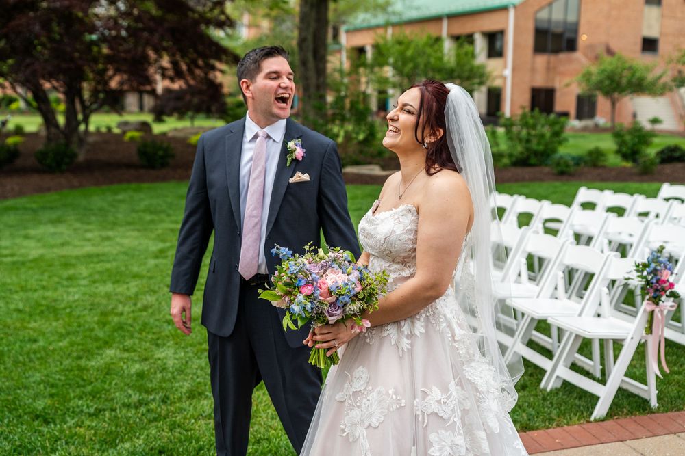 Newlyweds sharing joyful moments during outdoor wedding portraits on a lush green lawn.