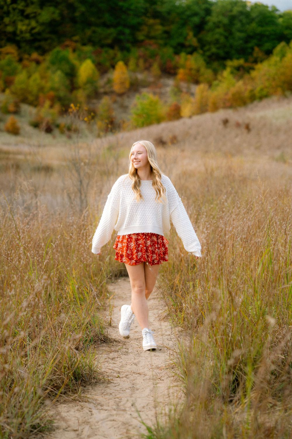 A series of images showing a person in a white top and red skirt walking through tall grass in a natural setting.