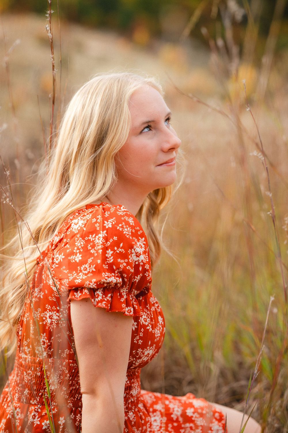 Candid outdoor portraits showcase a red floral dress among golden fall grasses and natural lighting.