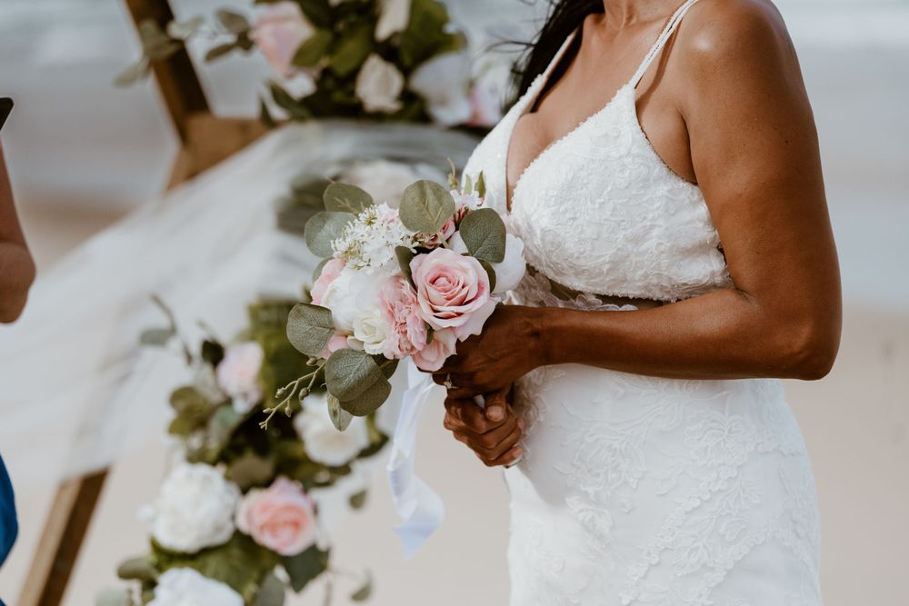Close up of bridal bouquet with pink roses and white flowers against wedding dress.