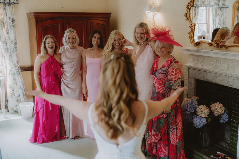 Wedding party celebrating in indoor venue with pink and floral dresses.