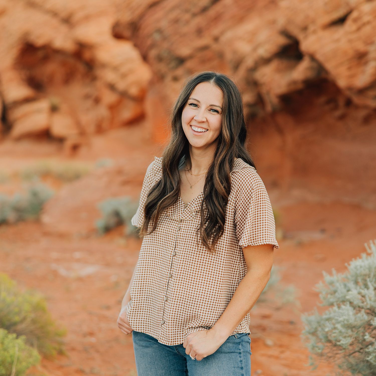 Portrait of person in white lace dress against desert backdrop at sunset.