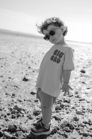 A small child plays on a rocky beach in black and white photography, captured from multiple angles.
