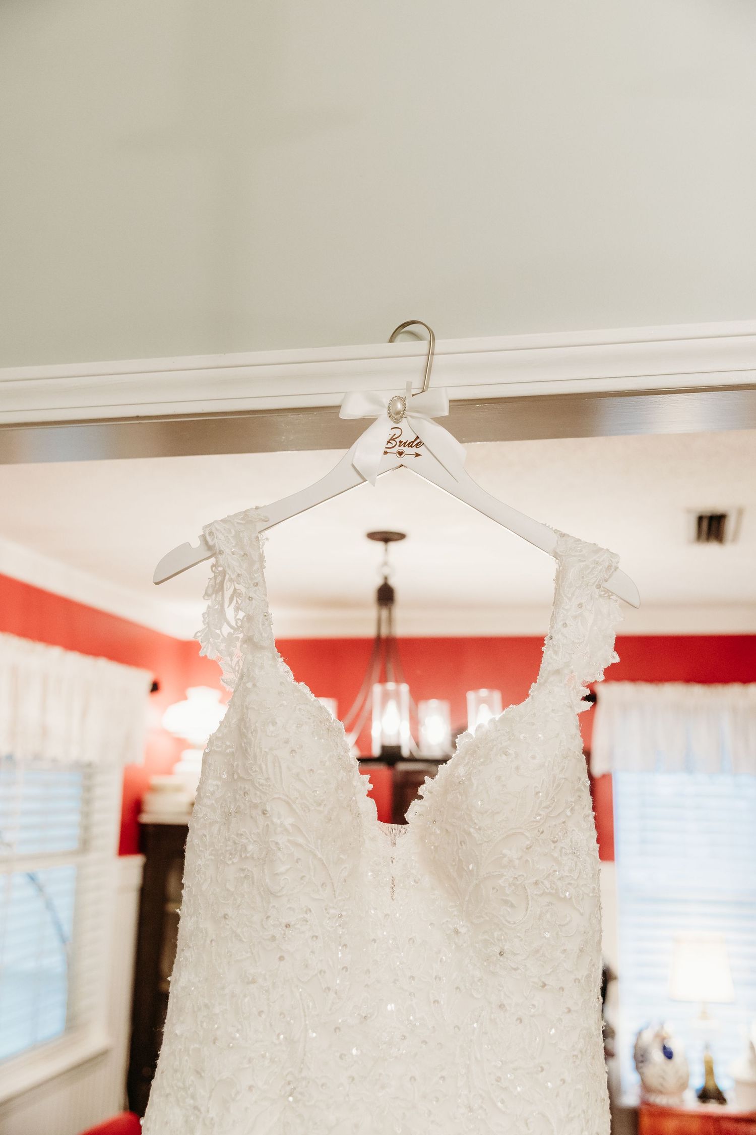 Close-up view of an elegant white beaded wedding dress hanging on display.