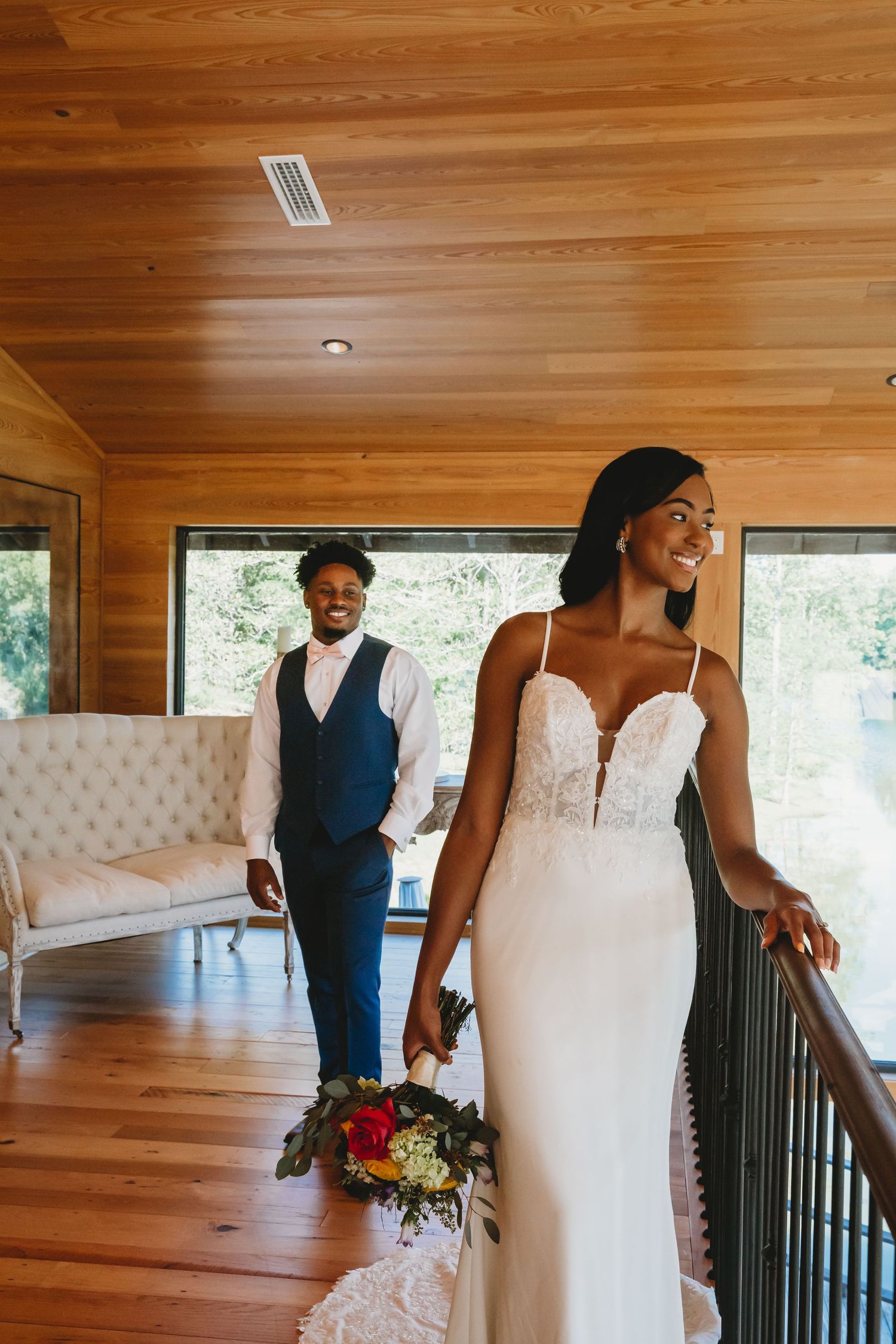 Wedding celebration in a rustic wooden interior with white tufted furniture and natural lighting.