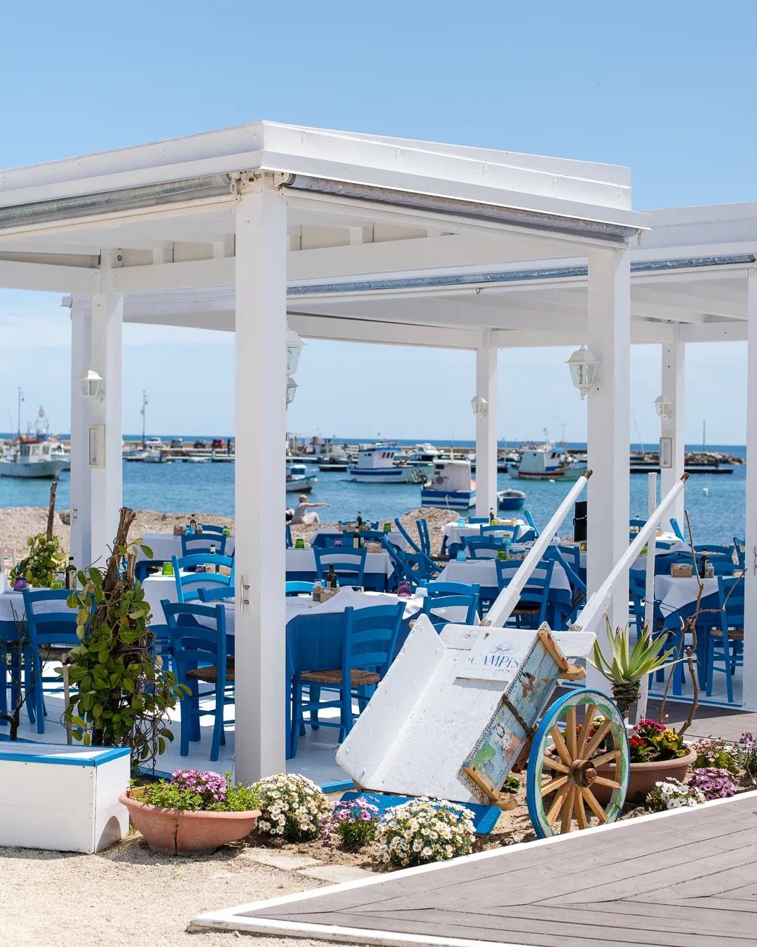 Boats docked at a bright white marina structure, showing a peaceful seaside harbour scene.