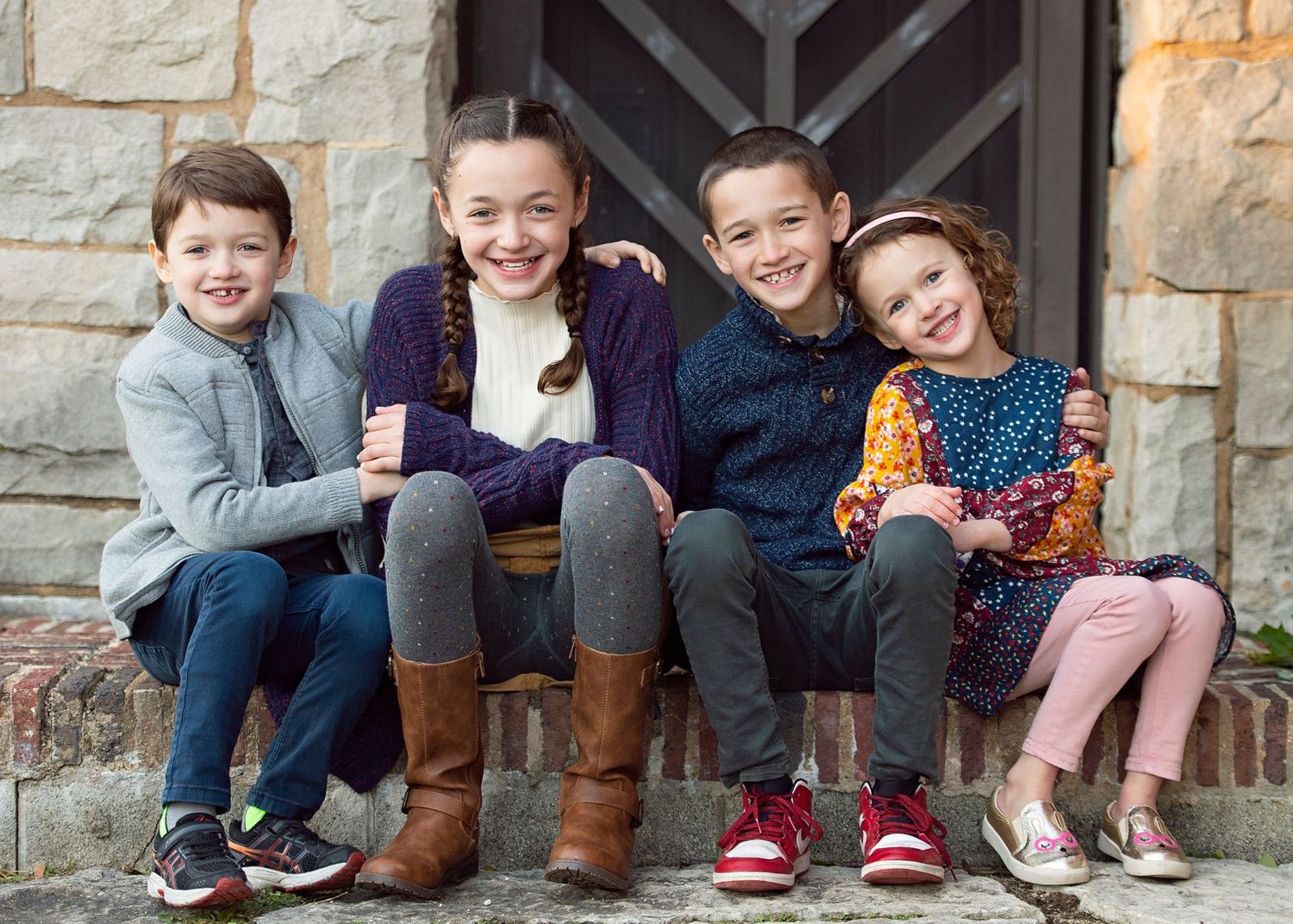 Four siblings sitting together on stone front steps