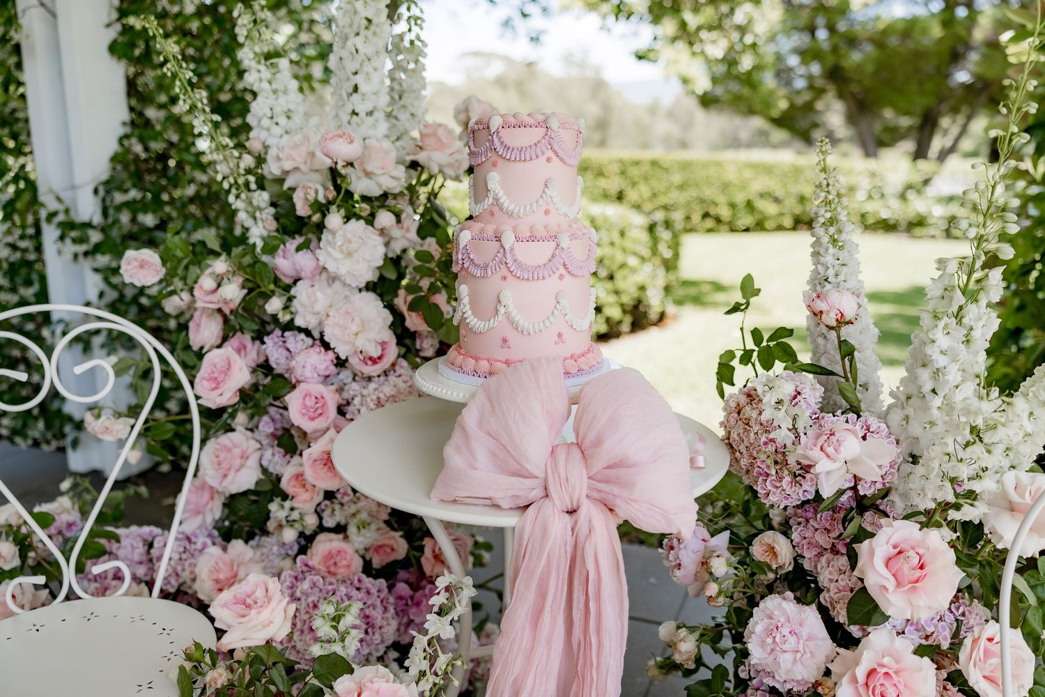 Elegant pink and white floral wedding decorations with roses and hydrangeas adorn an outdoor garden venue.