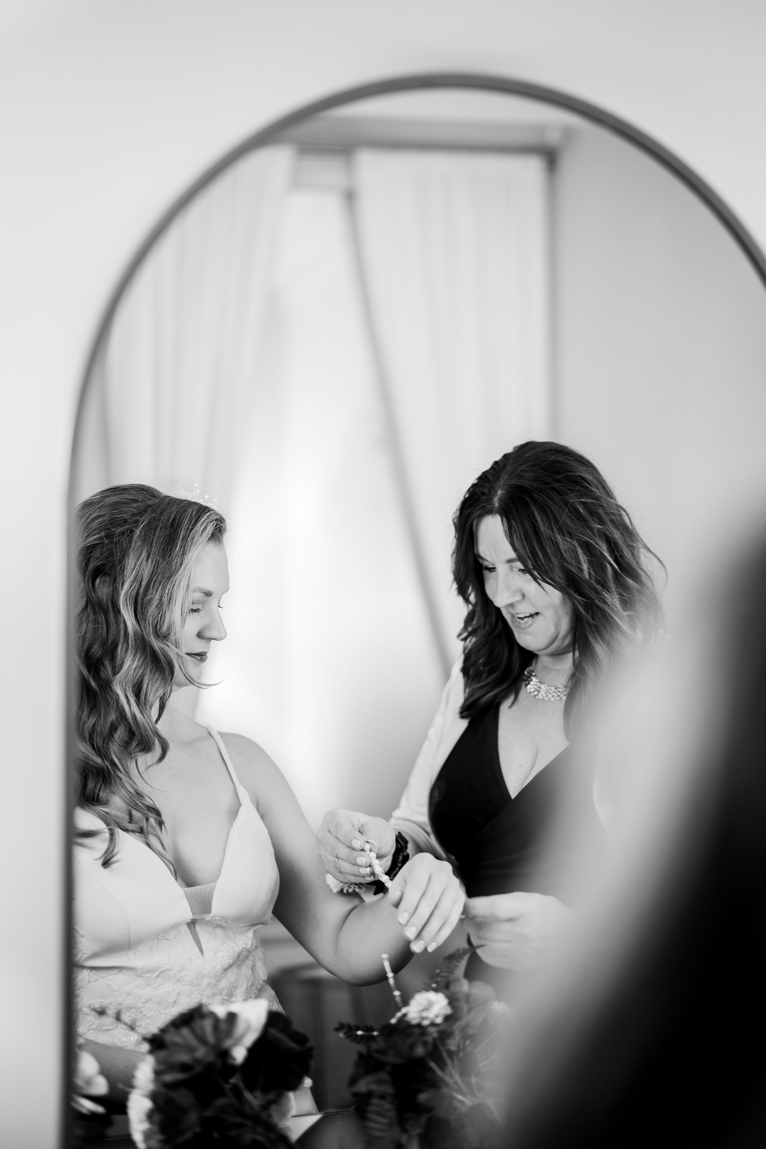 Black and white images of wedding preparation showing makeup application in soft natural light.