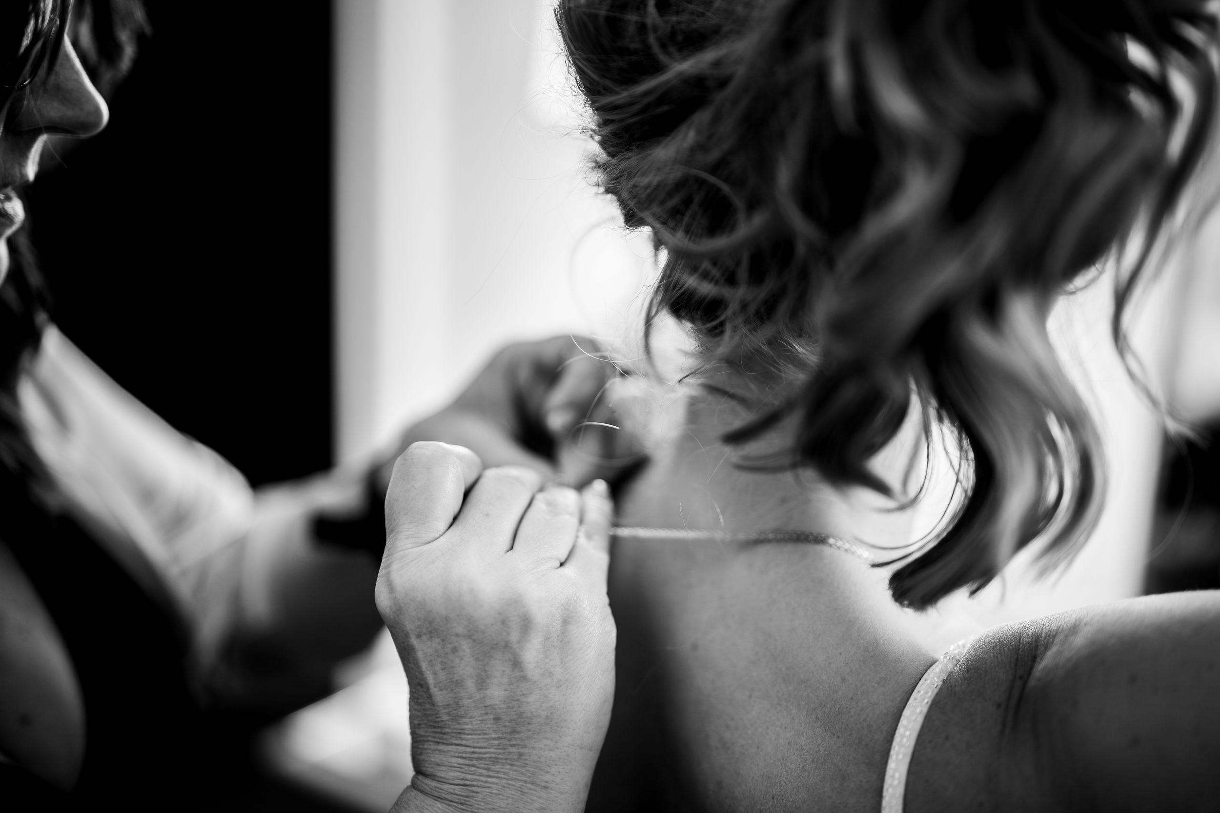 Black and white close-up shot of hands lacing up a dress or corset from behind.